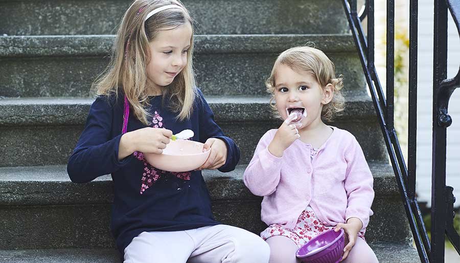 Two girls eating yogurt on stairs