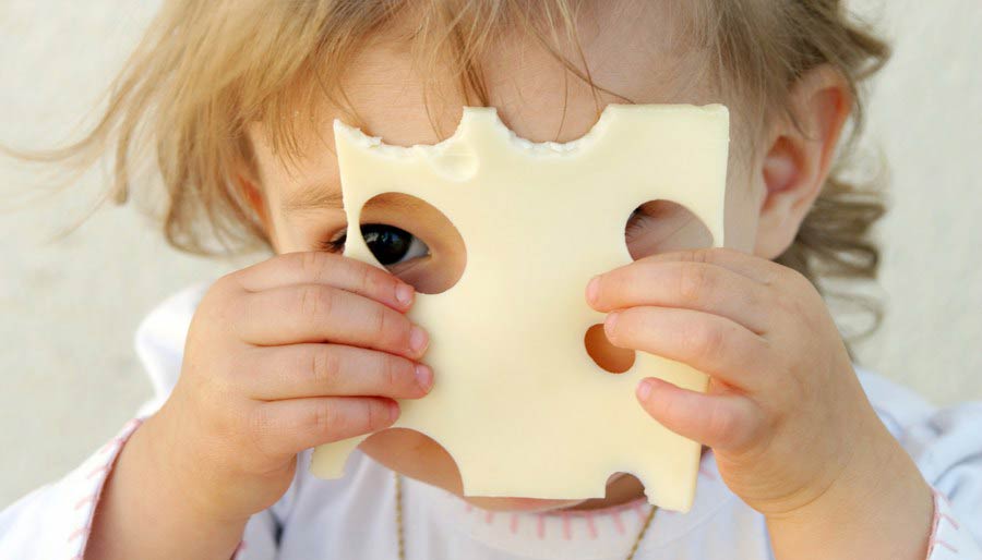 Little girl looking through cheese