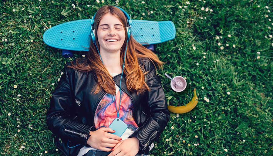 Girl laying in the grass resting head on skateboard with yogurt