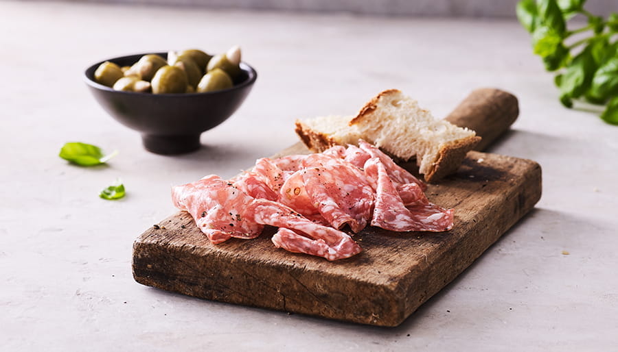 Salami on wooden board with olives