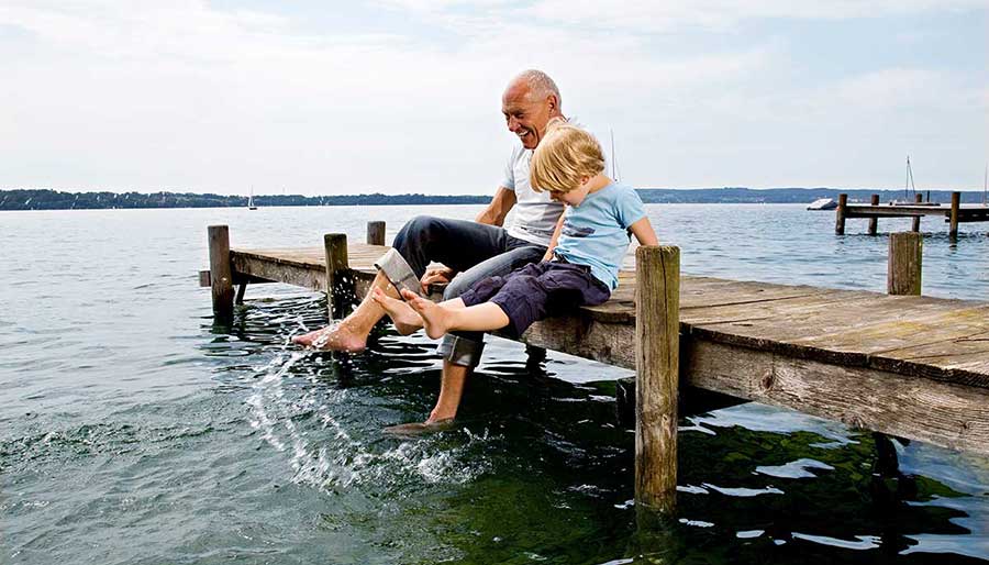 Elderly man and boy with feet in water