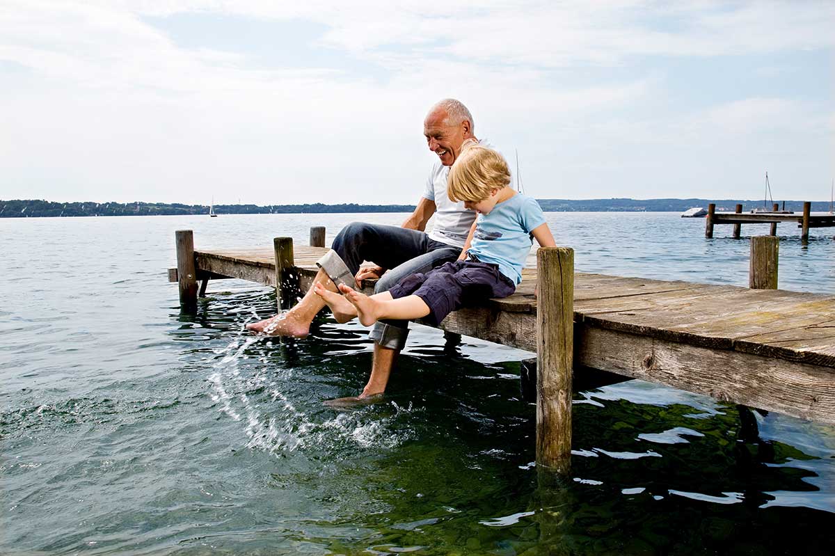 Boy and man splashing water by a lake