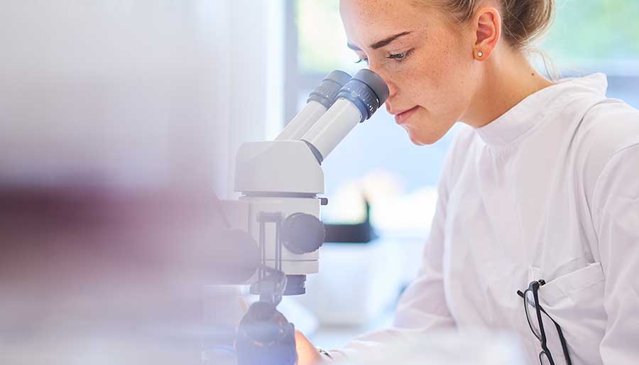 Woman in science lab looking into microscope