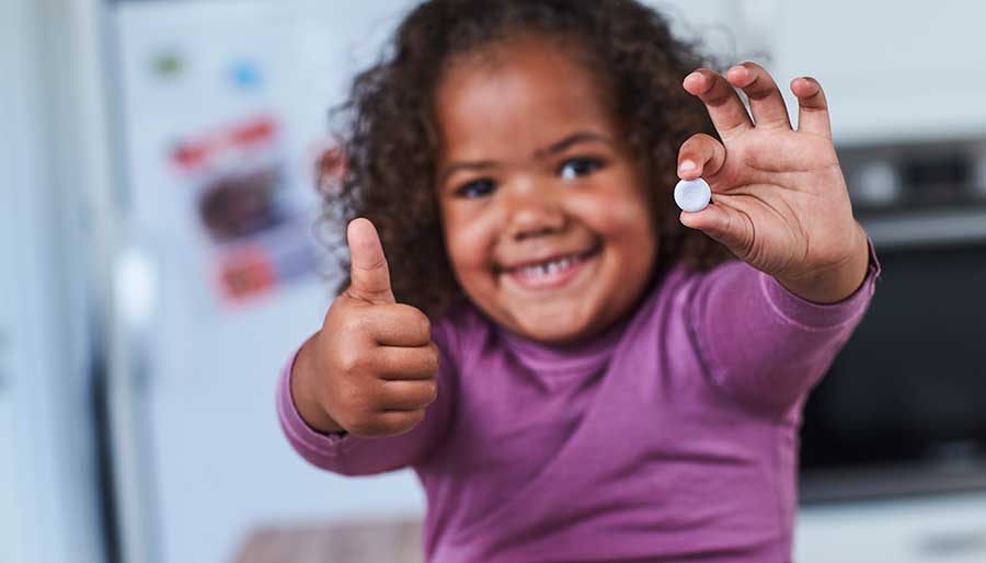 Smiling girl holding probiotic pill